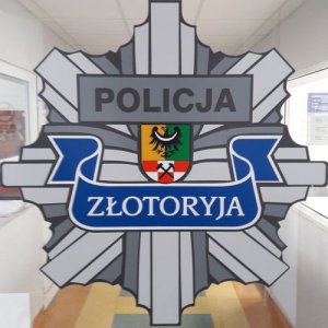 Przeszklone drzwi, na których widnieje grafika w kształcie gwiazdy- policyjnej odznaki z napisem POLICJA, Złotoryja i herbem powiatu złotoryjskiego