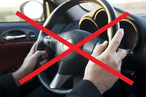 ręce na kierownicy, zdjęcie przekreślone czerwonym znakiem X