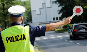 policjant z wyciągniętą tarczą do zatrzymywania pojazdów