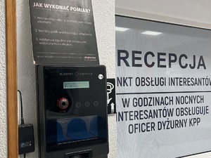 pomieszczenie recepcji komendy policji w Złotoryi, zamontowane na ścianie urządzenie do pomiaru alkoholu