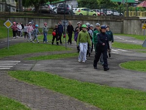 za policjantką idą dzieci po placu do zdawania egzaminu na kartę rowerową