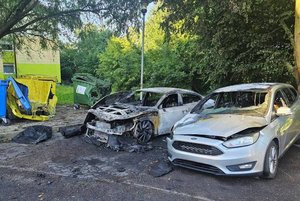 na parkin stoją dwa spalone samochody osobowe, oraz trzy nadpalone kosze na śmieci.