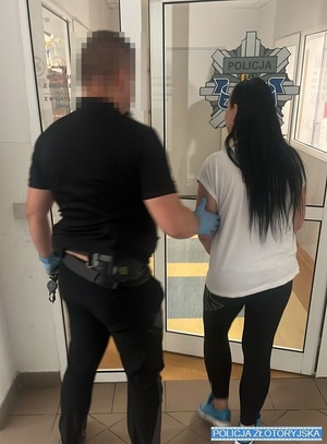 policjant prowadzi zatrzymaną kobietę