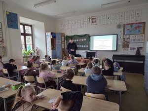 Policjant na spotkaniu z dziećmi przedstawia elementy bezpiecznych ferii zimowych