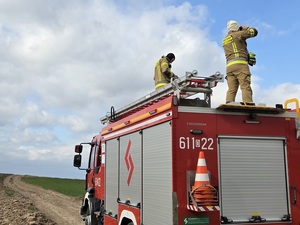 Dwóch strażaków stojących na wozie strażackim