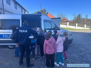 Dzieci stojące przy radiowozie policyjnym