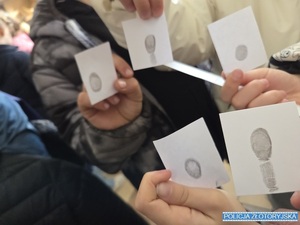 Dzieci trzymają kartki z odciśniętymi odciskami palców