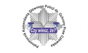 Odznaka policyjna w kształcie gwiazdy ze wstęgą przebiegającą przez jej środek. Na wstędze napis Czy wiesz, że? Wkoło odznaki napis Pełnomocnik Komendanta Głównego Policji do spraw Ochrony Praw Człowieka