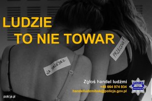 Dwie tulące się osoby, na plecach maja naklejone kawałki papieru z napisem &quot;na sprzedaż&quot;, &quot;przecena&quot;. Na zdjęciu znajduje się hasło Ludzie to nie towar, Zgłoś handel ludźmi +48664974934 handelludzmibsk@policja.gov.pl