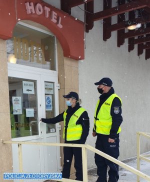 Umundurowani policjanci stoją przed wejściem do hotelu