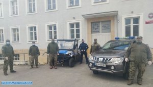 Policjant i leśnicy pozują do wspólnego zdjęcia