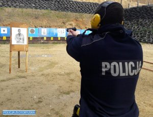 Policjant strzela zza zasłony