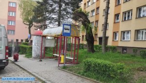 Przystanek autobusowy, w tle bloki mieszkalne