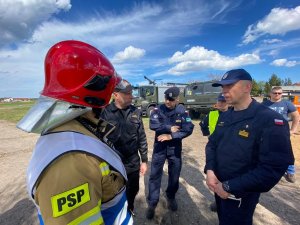 Grupa rozmawiających ze sobą strażaków i policjantów