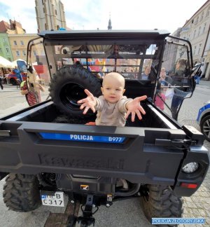 Dziecko siedzi w pojeździe, wyciąg ręce w kierunku fotografa