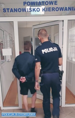 Policjant prowadzi zatrzymanego mężczyznę